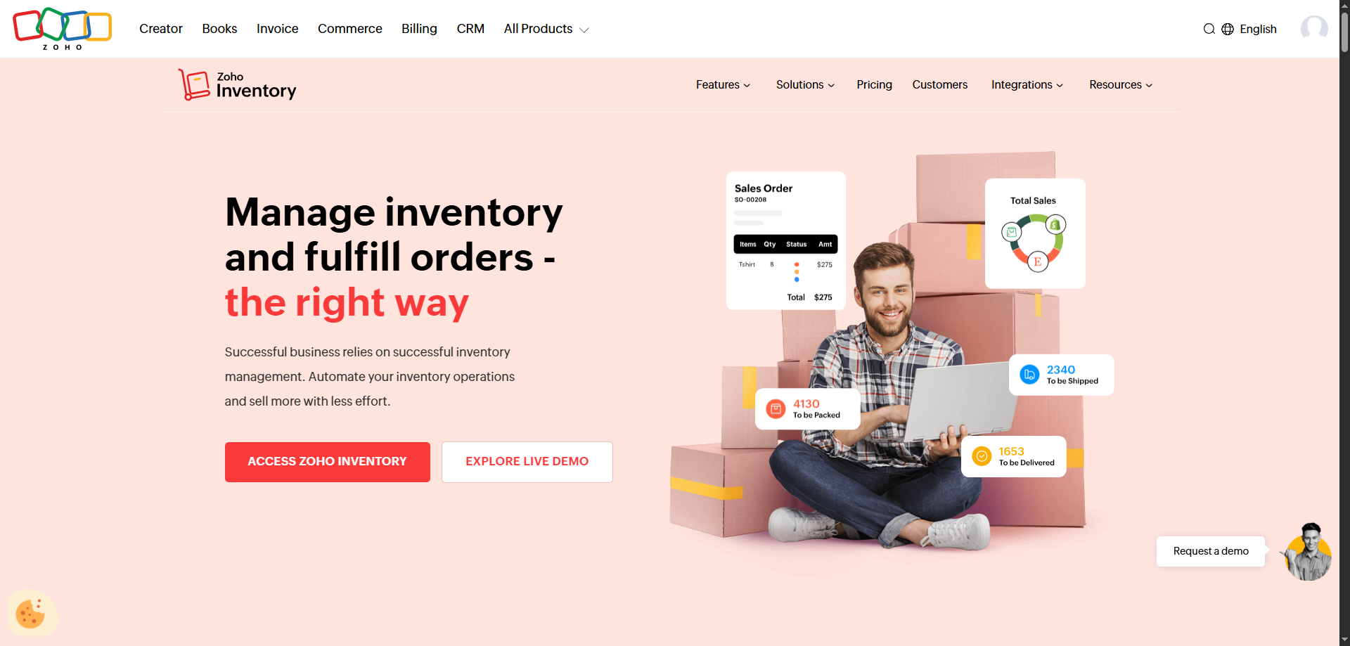 Smiling man with laptop sits among pink boxes and sales graphics, showcasing Zoho Inventory as top food distribution software.