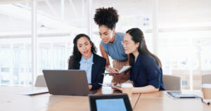 Three professional women collaborate in a bright office - Shopify Plus Alternatives