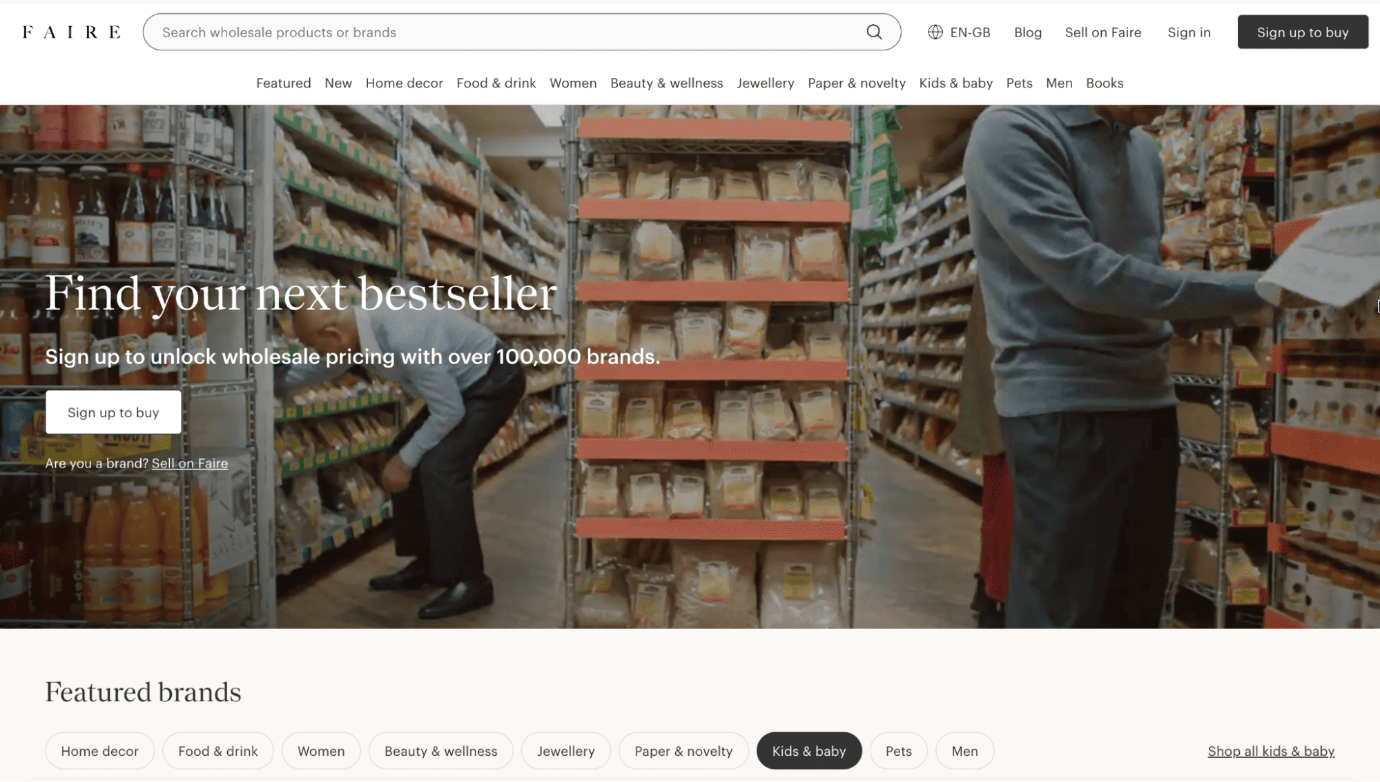Two shoppers browse a grocery store aisle filled with packaged foods; promo text invites users to unlock wholesale pricing on Faire.