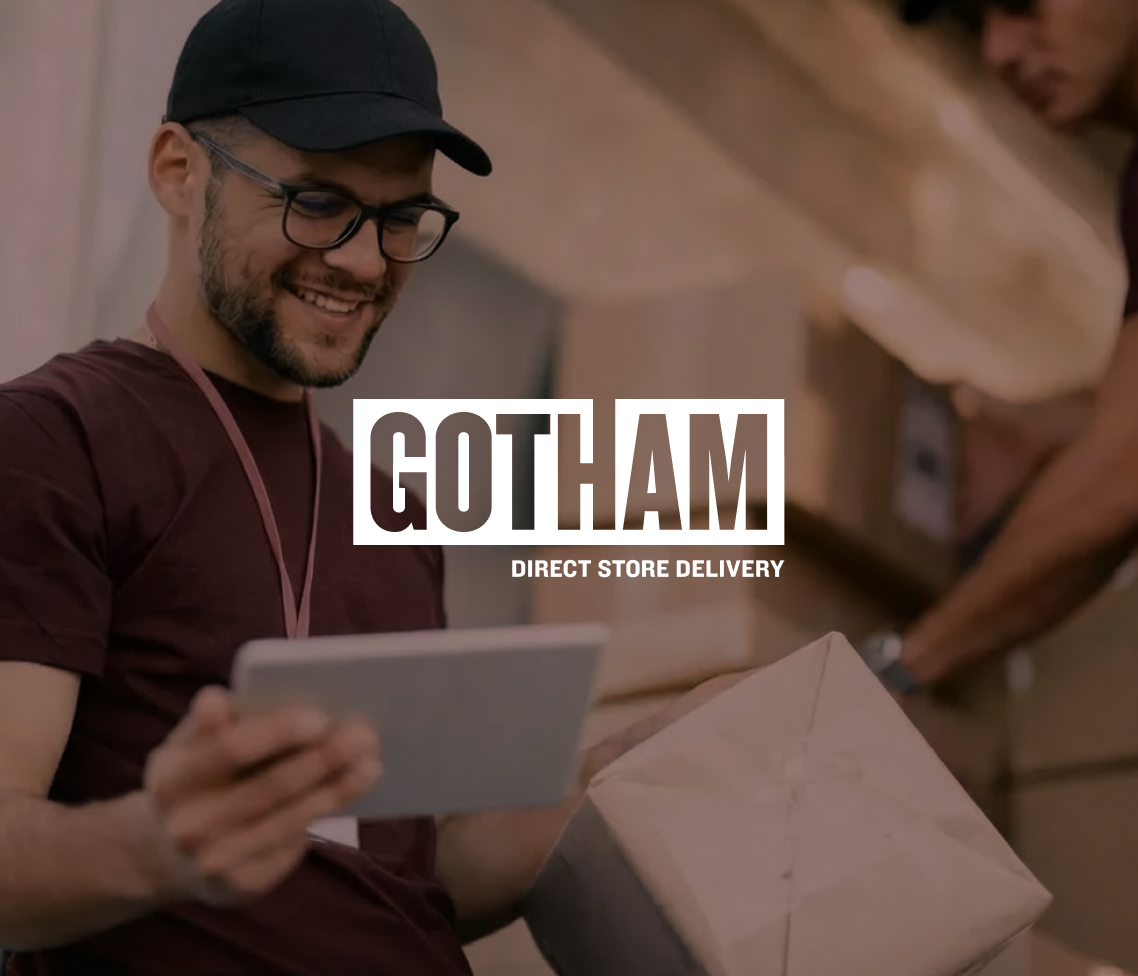 A cheerful delivery worker with glasses and a cap holds a tablet and package, while another moves boxes. GOTHAM DIRECT STORE DELIVERY text appears.