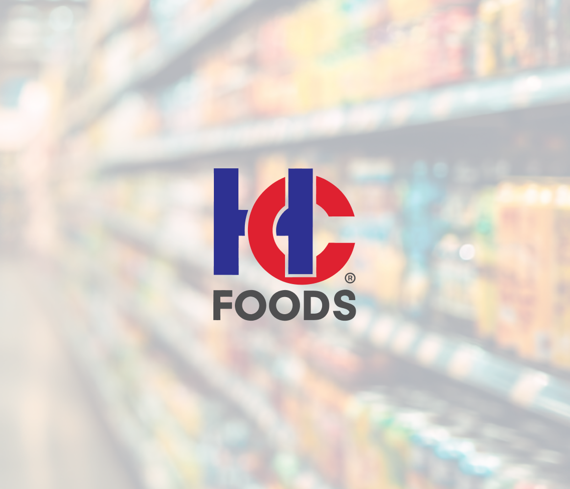 Centered against a blurred grocery store aisle, the HC Foods logo stands out in blue and red amid shelves of assorted products.